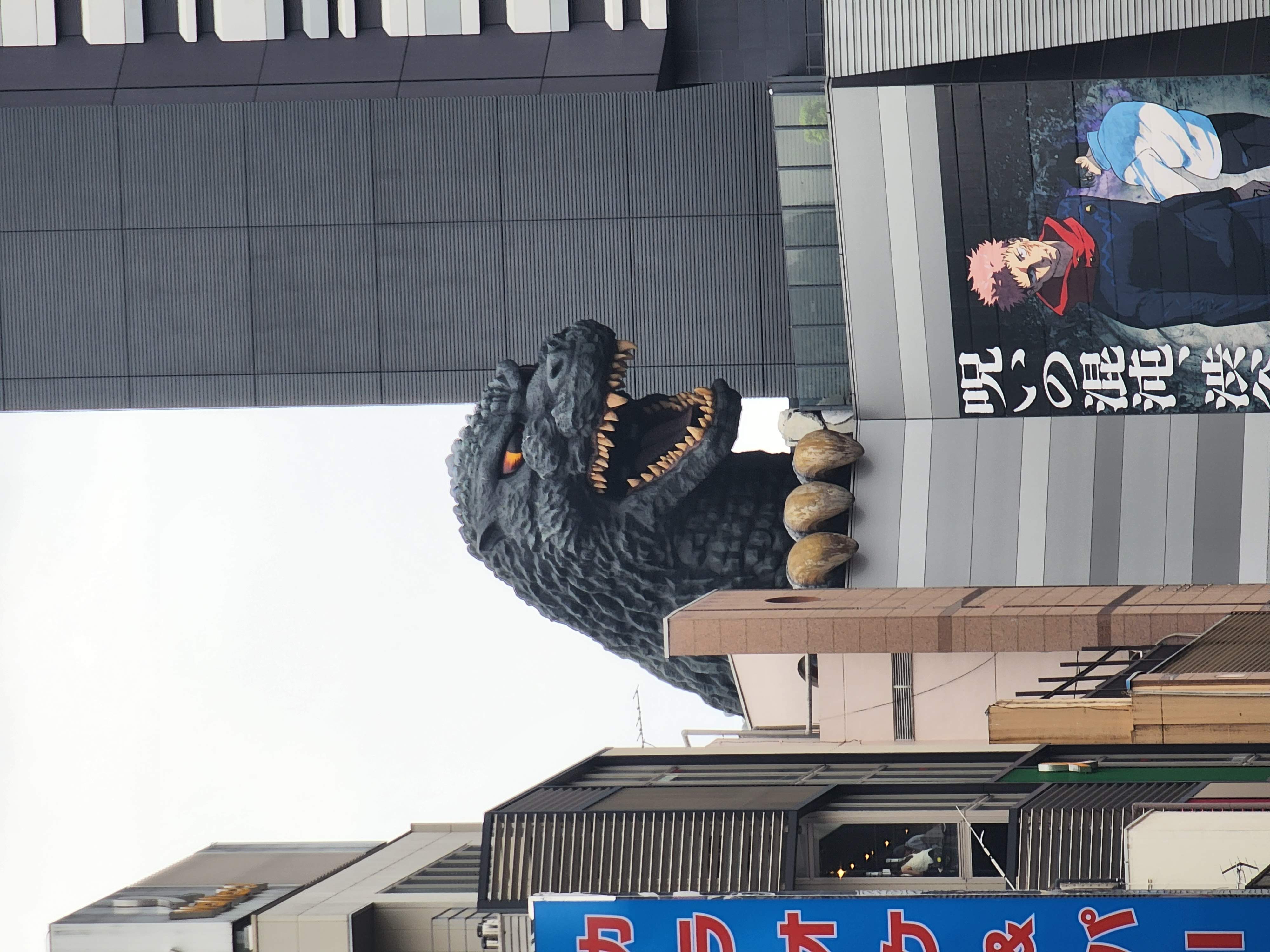Godzilla perched on a building showing just the head with a mean expression